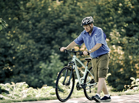 Man walking with bicycle wearing helmet